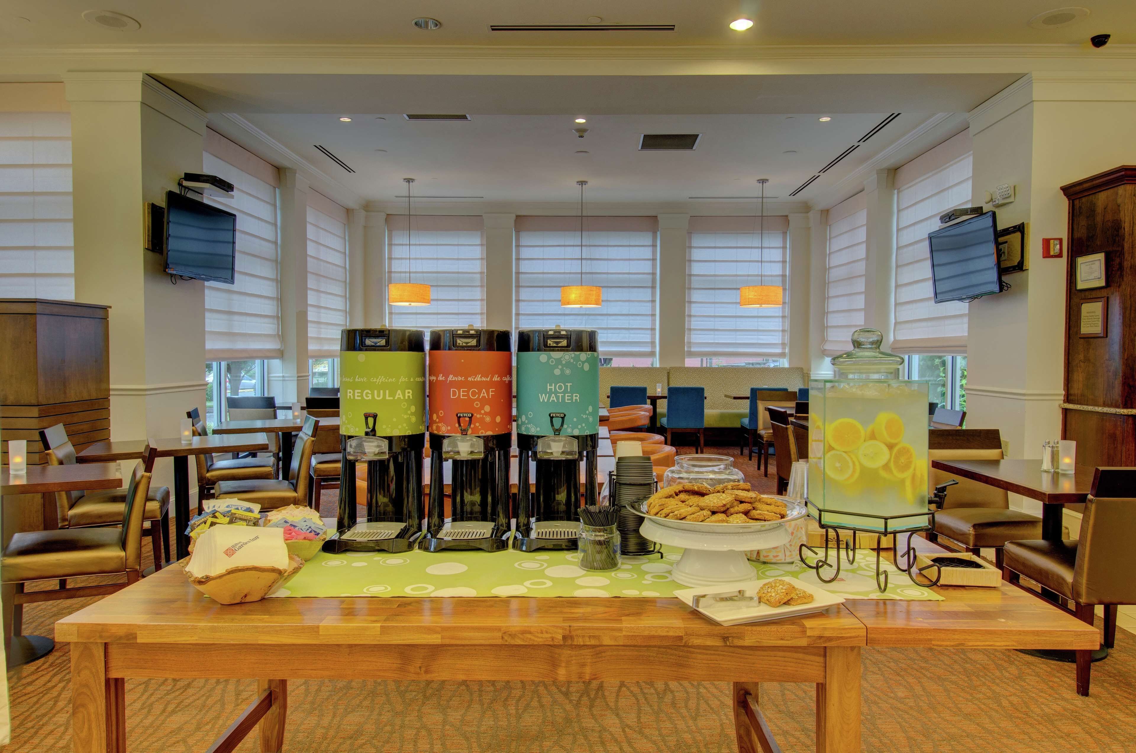 A hotel lobby with a buffet table, coffee machines, and seating areas.