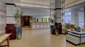 A spacious lobby with a reception desk, seating area, and potted plants. - Hilton Garden Inn Norwalk (Norwalk)