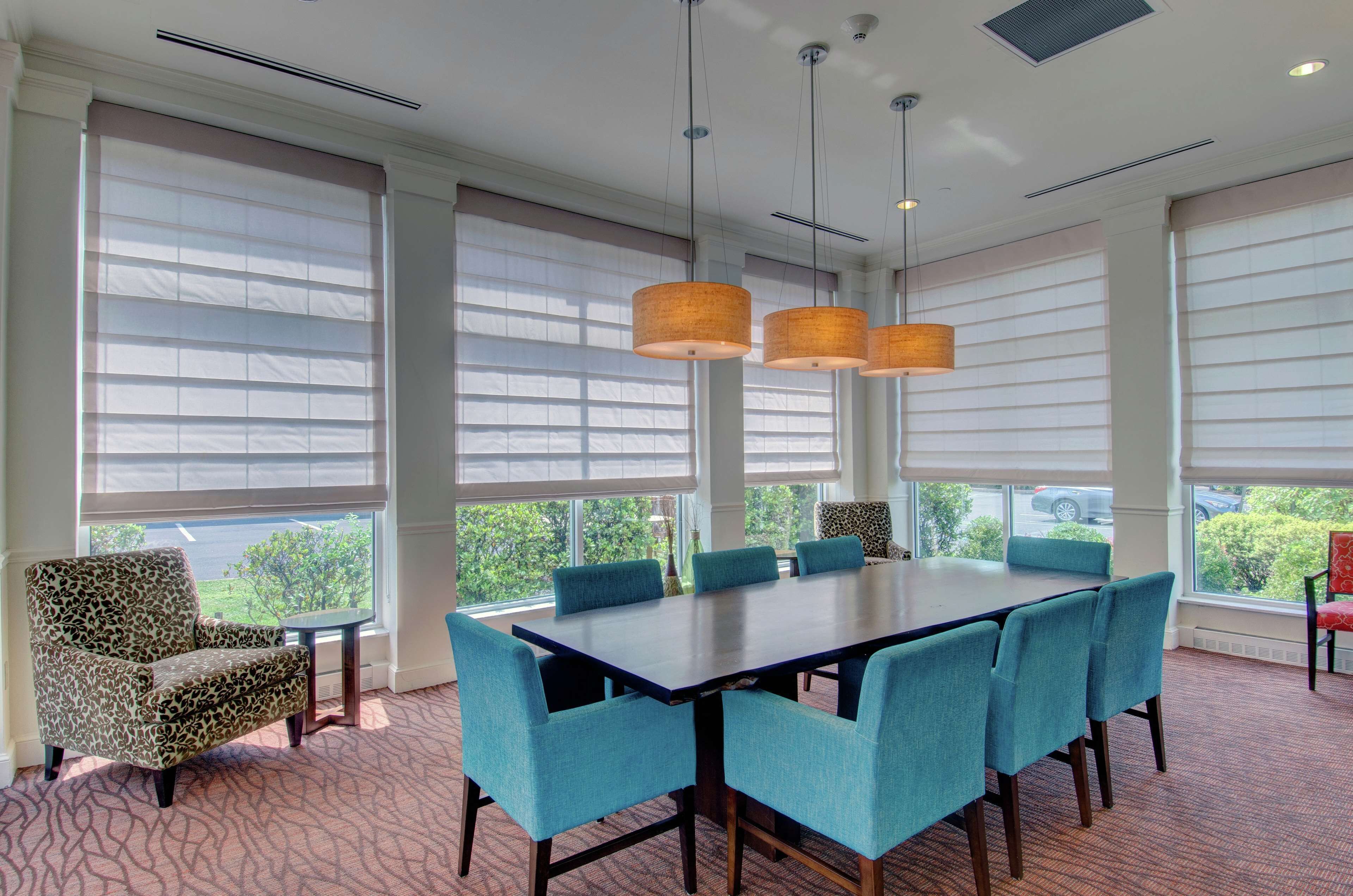 A conference room with a large table, six chairs, and three hanging lamps.