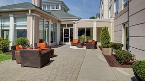 A spacious outdoor patio with wicker furniture and potted plants. - Hilton Garden Inn Norwalk (Norwalk)