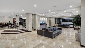 Un vestíbulo amplio con zona de estar, mostrador de recepción y una escalera moderna.