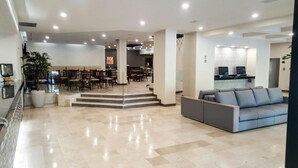 Un vestíbulo amplio con un diseño moderno, que cuenta con una zona de estar con sofás y una escalera que lleva a un comedor.