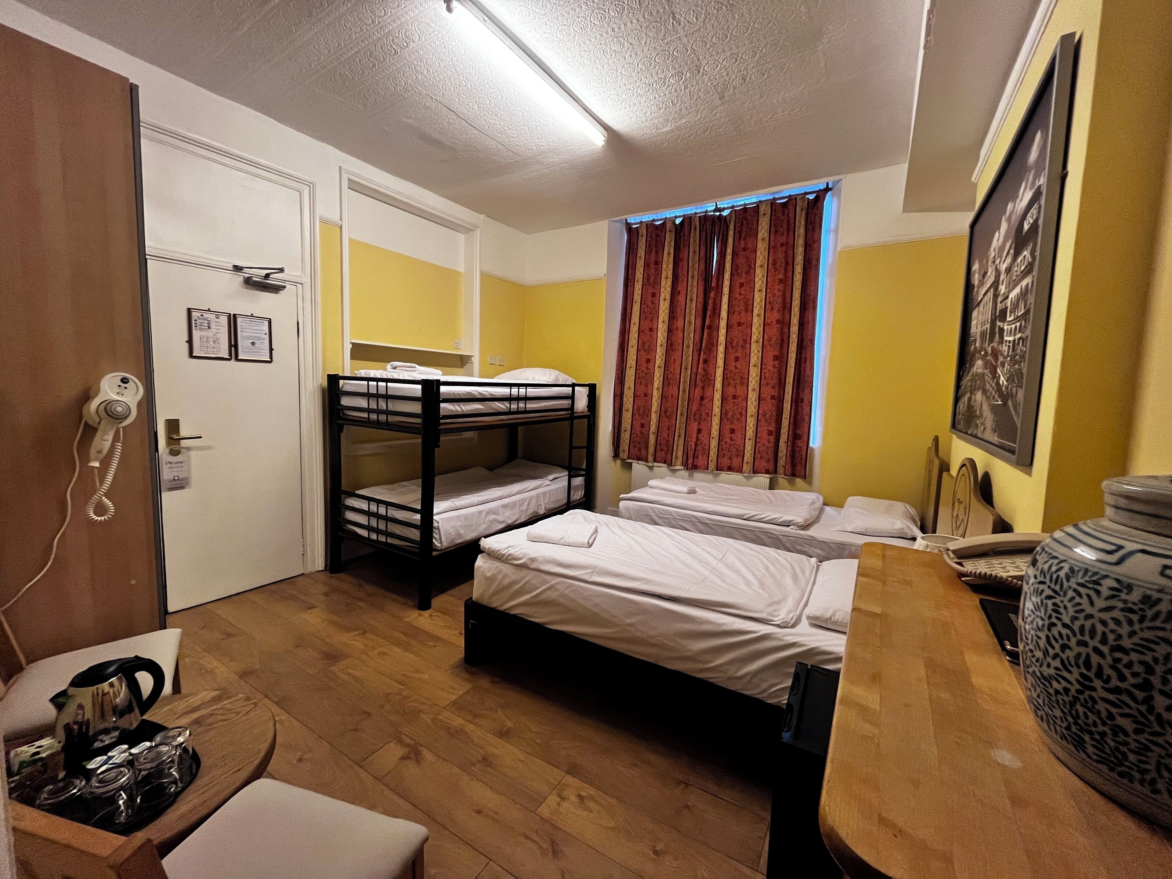 Un dormitorio con literas, un escritorio con teléfono y una ventana con cortinas.