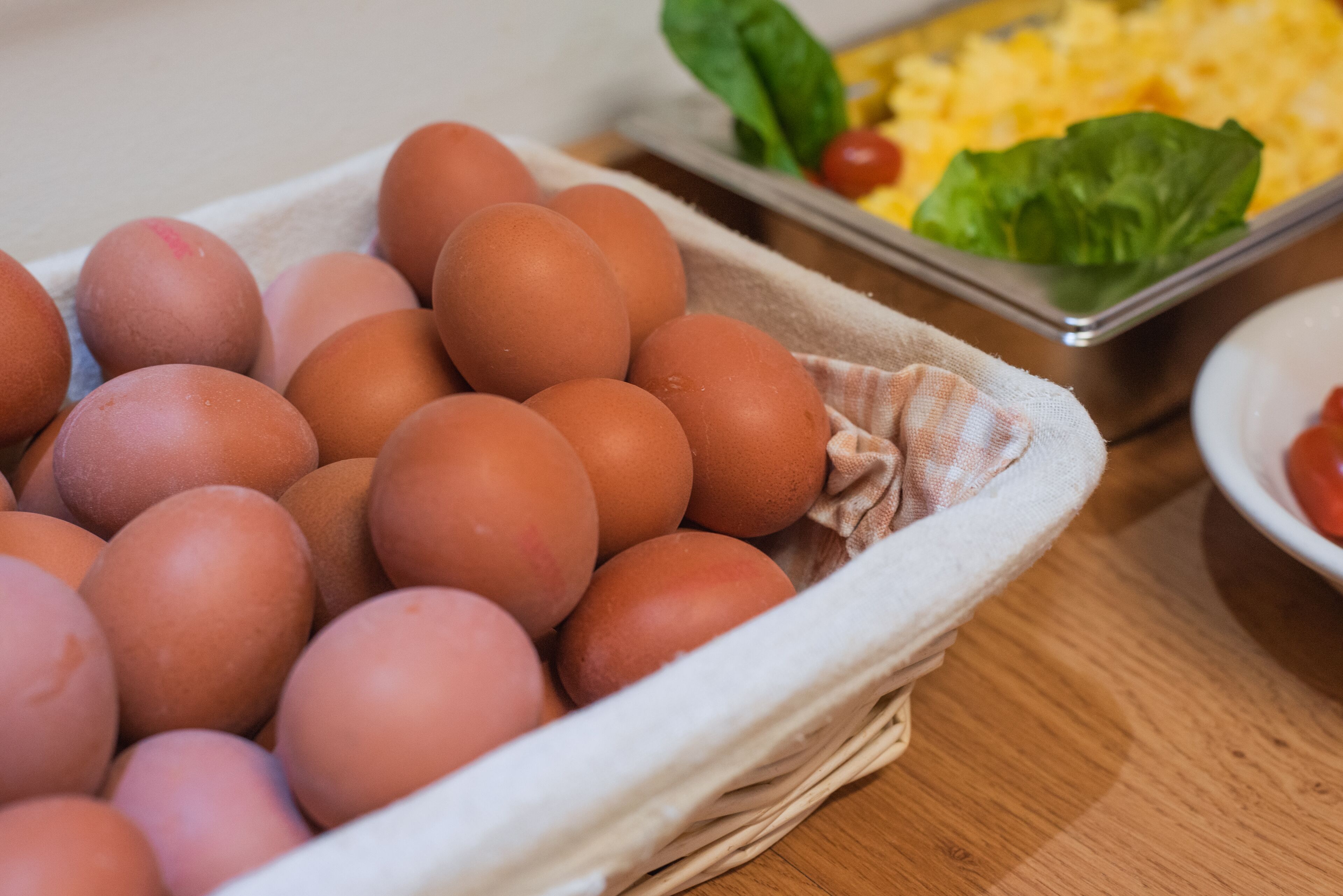 A tray of brown eggs in a basket on a wooden table.