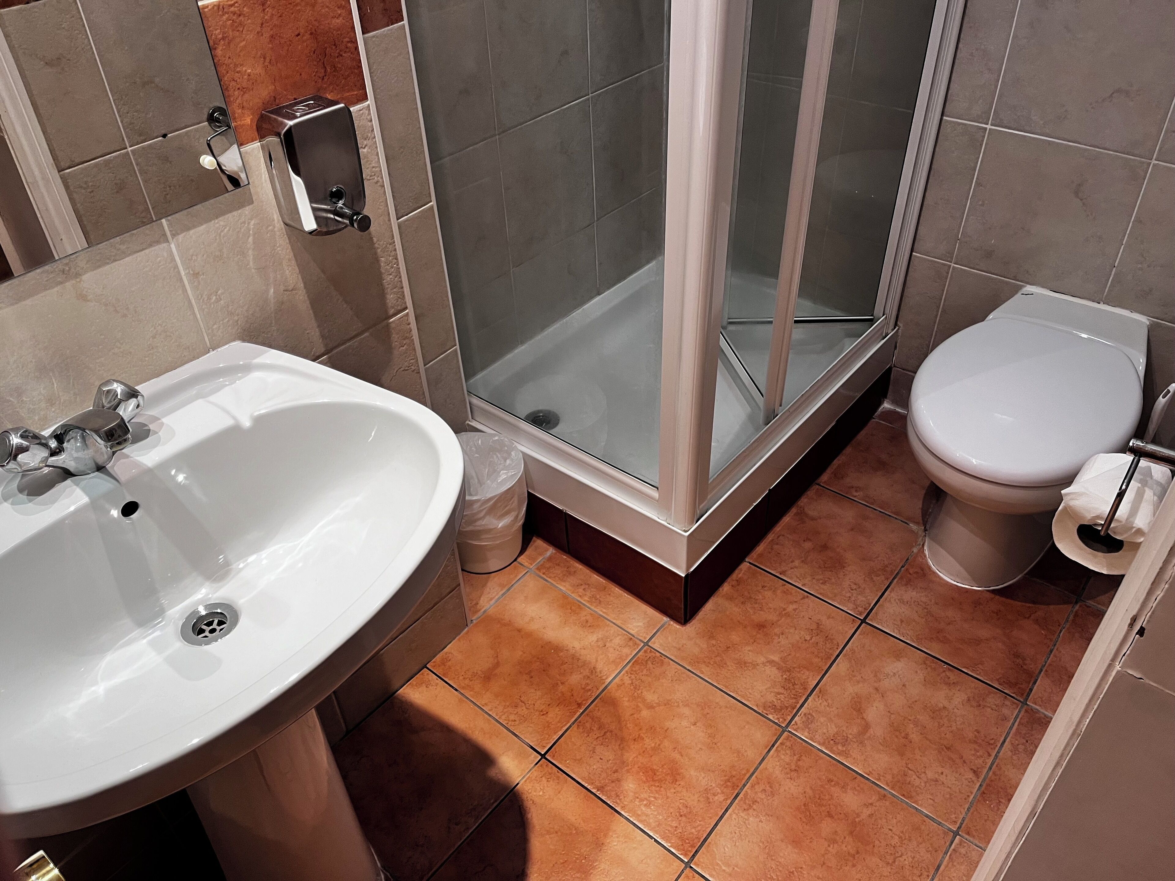 Een badkamer met een wastafel, toilet en douchecabine.