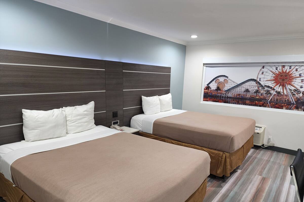 Habitación de hotel con dos camas, un mural grande de un parque temático y un diseño moderno.