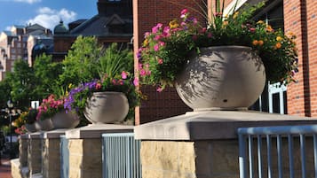 A row of planters with flowers along a brick building's exterior.