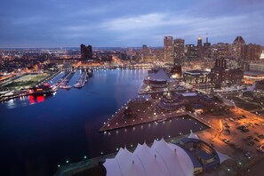 A cityscape with a river, modern buildings, and a waterfront area with tents and a large dome structure.