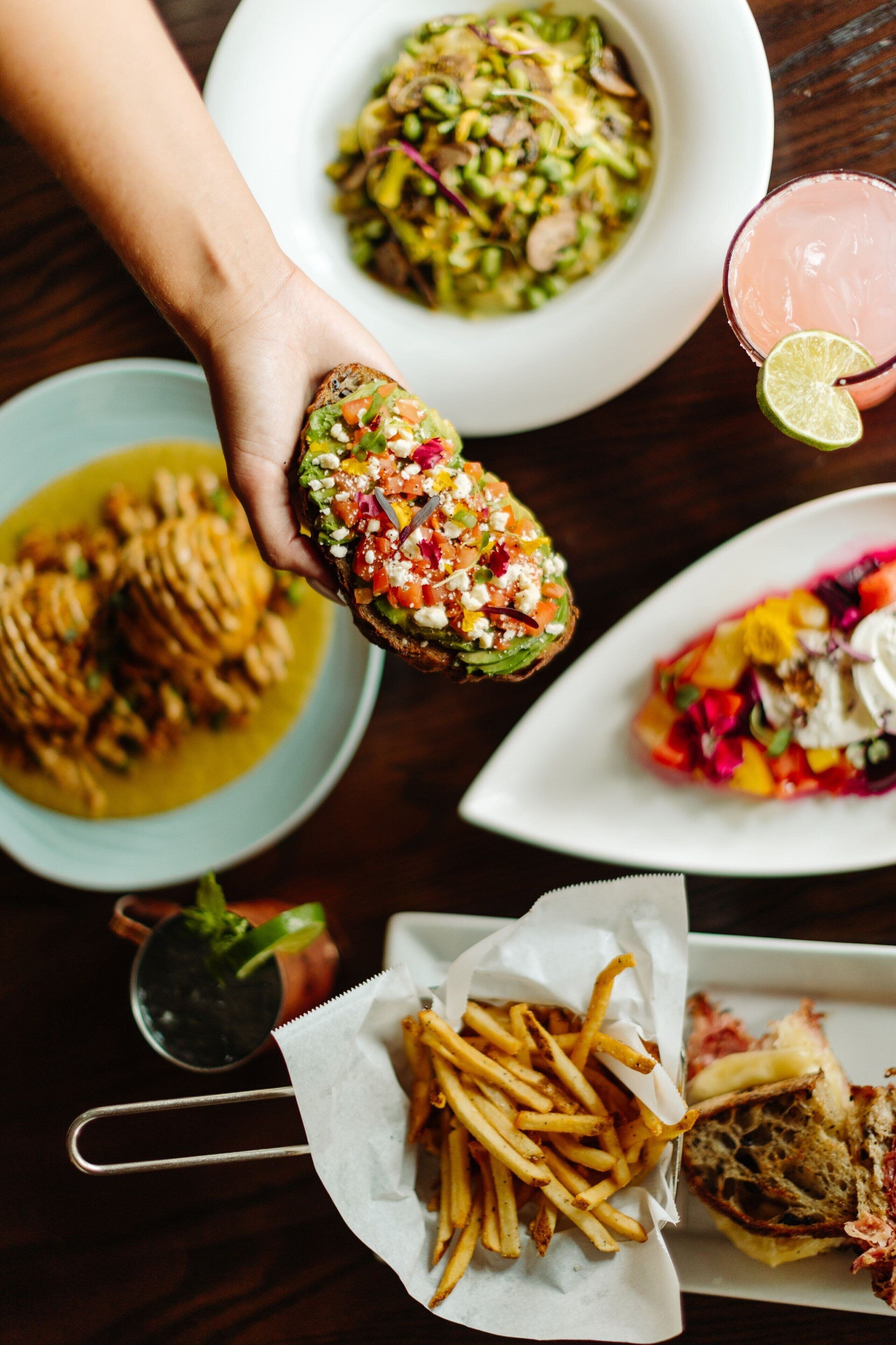 A variety of dishes including a stuffed bread, a salad, and a sandwich, along with a drink and fries.