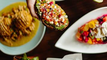 A variety of dishes including a stuffed bread, a salad, and a sandwich, along with a drink and fries.