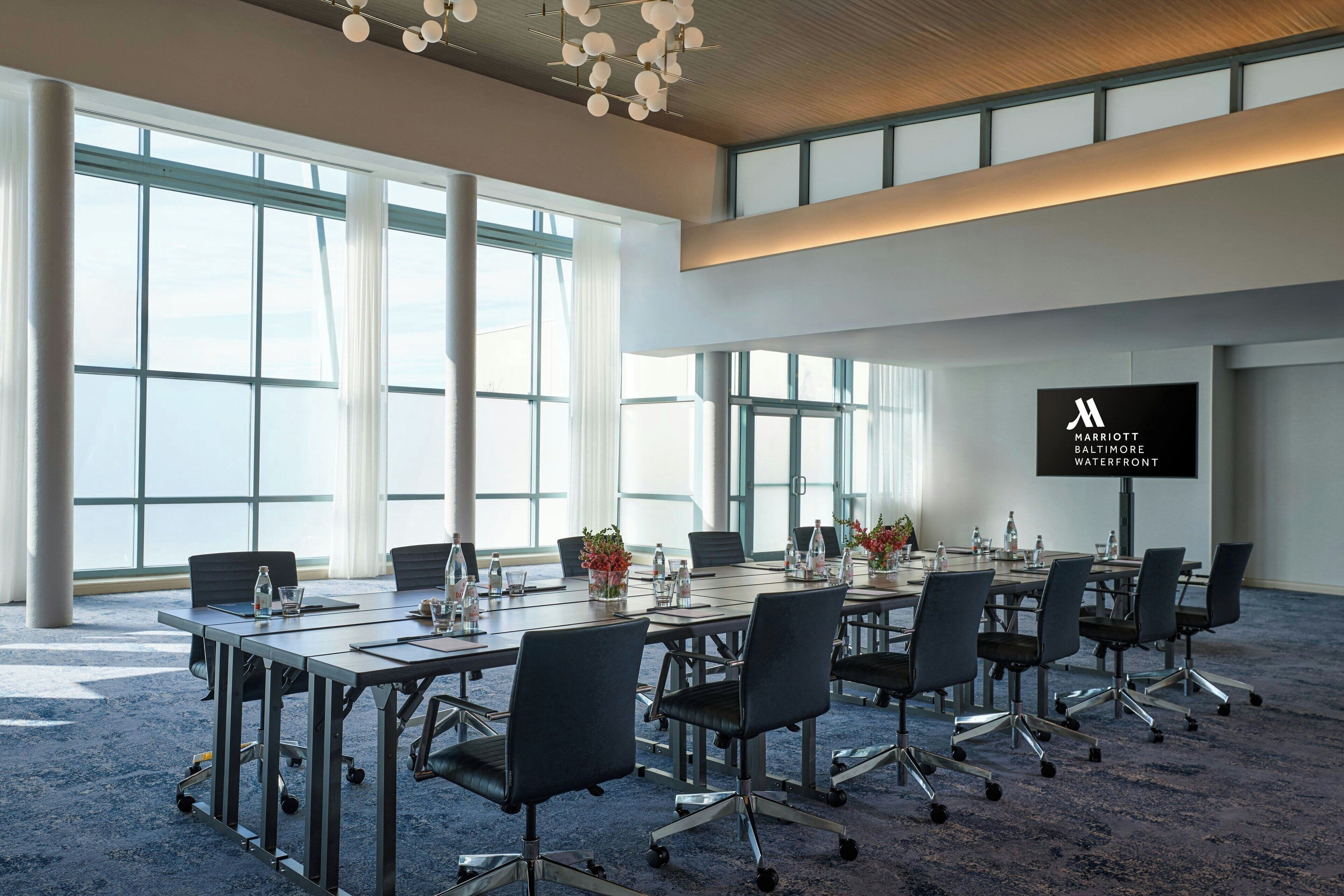 A conference room with large windows, a flat-screen TV, and a carpeted floor.