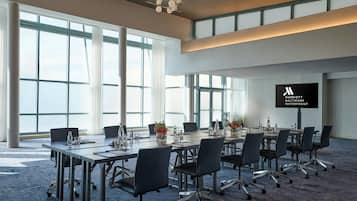 A conference room with large windows, a flat-screen TV, and a carpeted floor.