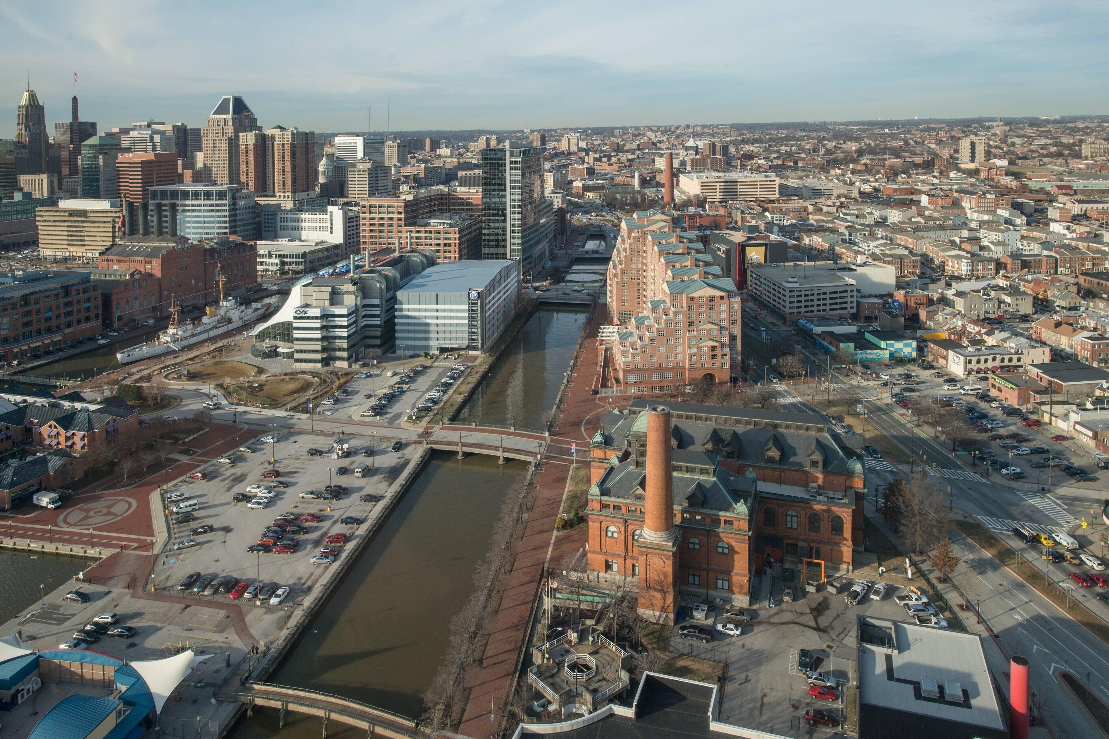 An aerial view of a cityscape with a prominent red brick building, a river, and modern high-rise buildings.