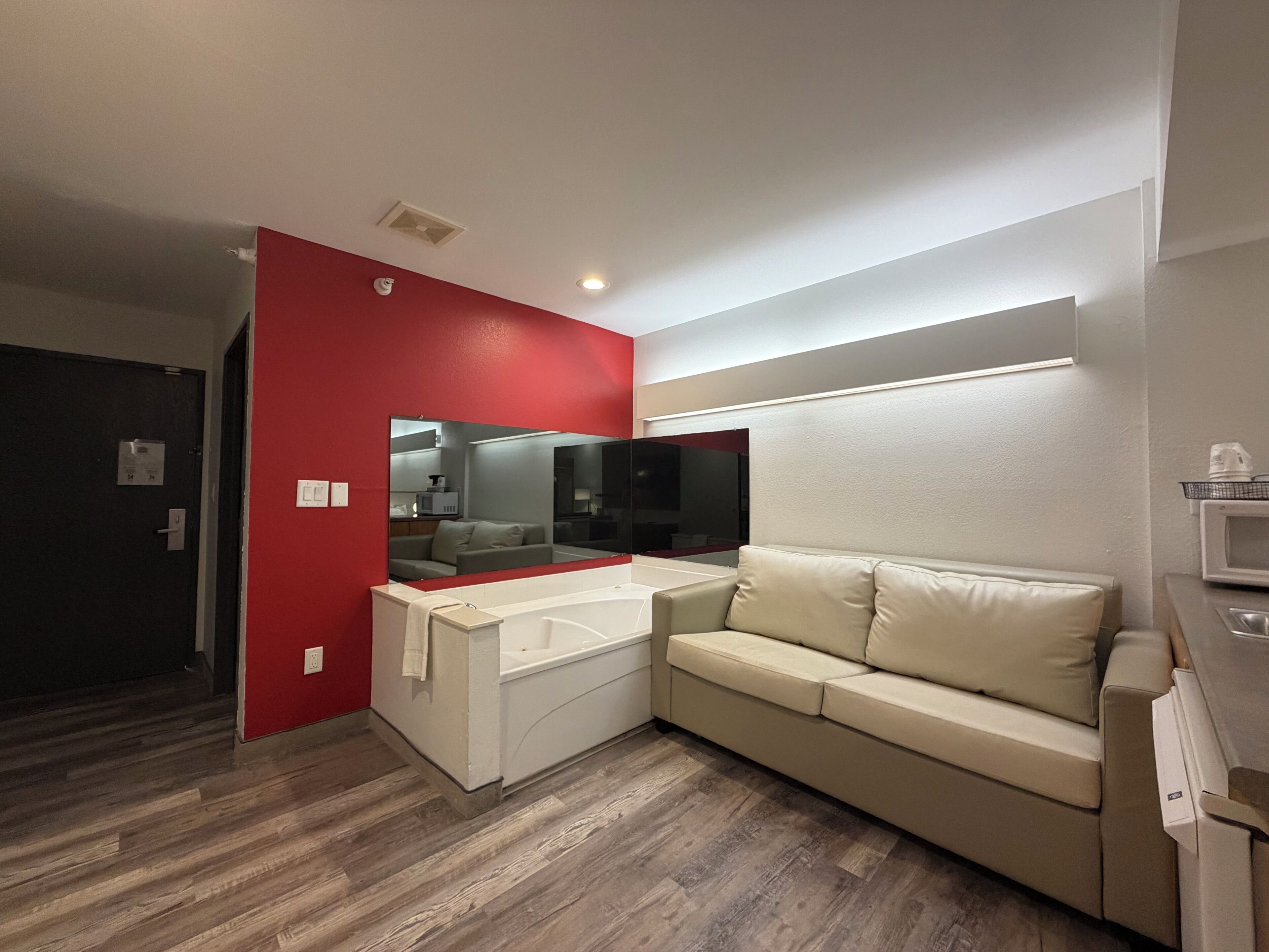 A modern bathroom with a white sink, a beige sofa, and a large mirror.
