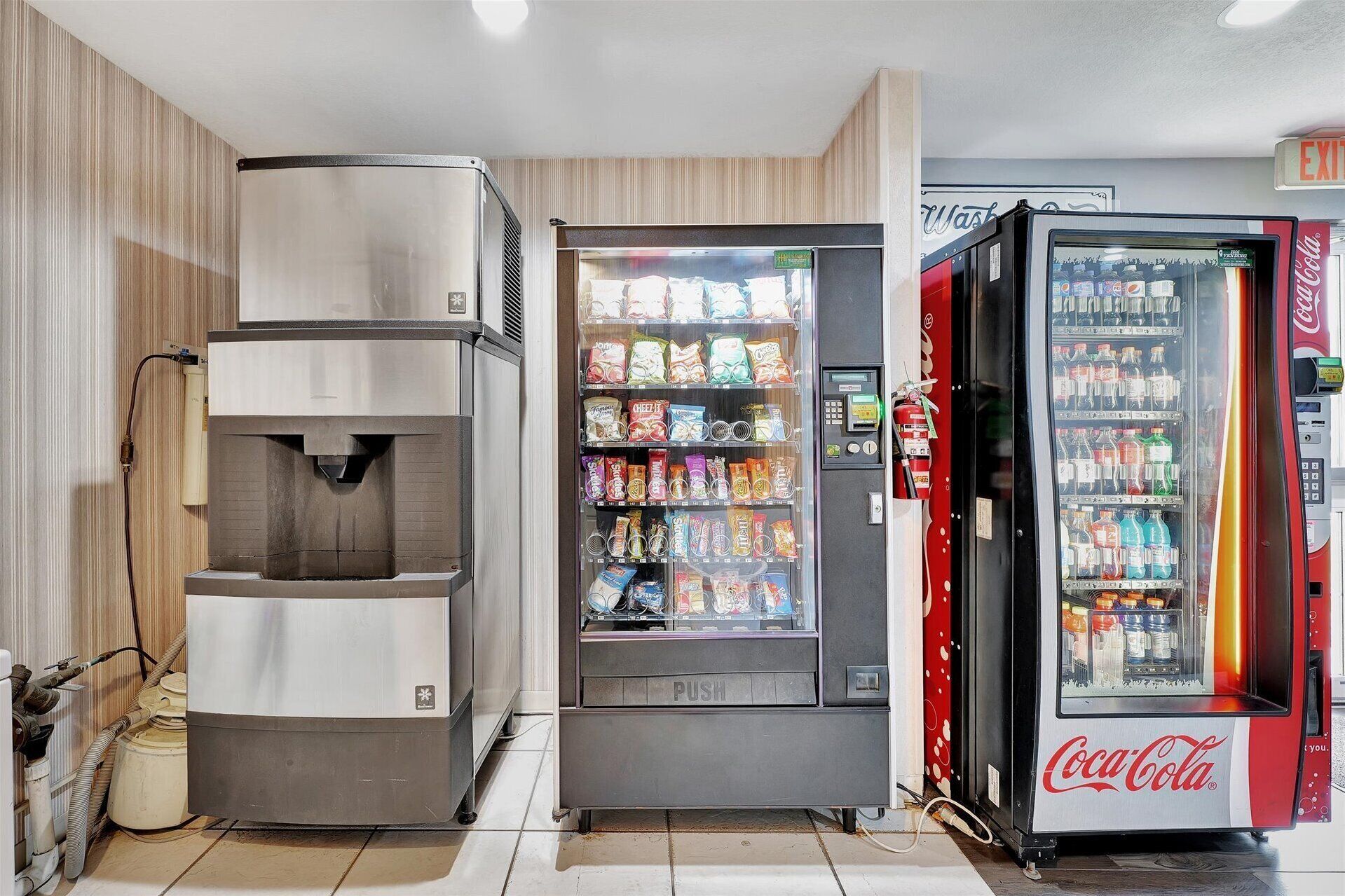 Zona de máquinas expendedoras con dispensador de agua, máquina de aperitivos y refrigerador de Coca-Cola.