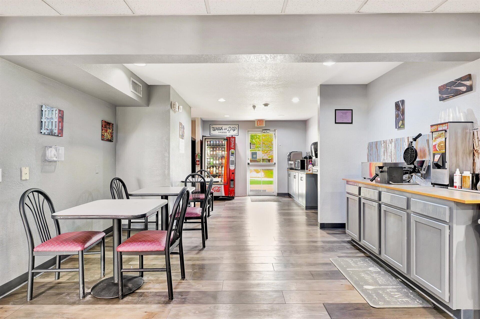 A clean, modern restaurant with a long counter, seating area, and a visible exit sign.