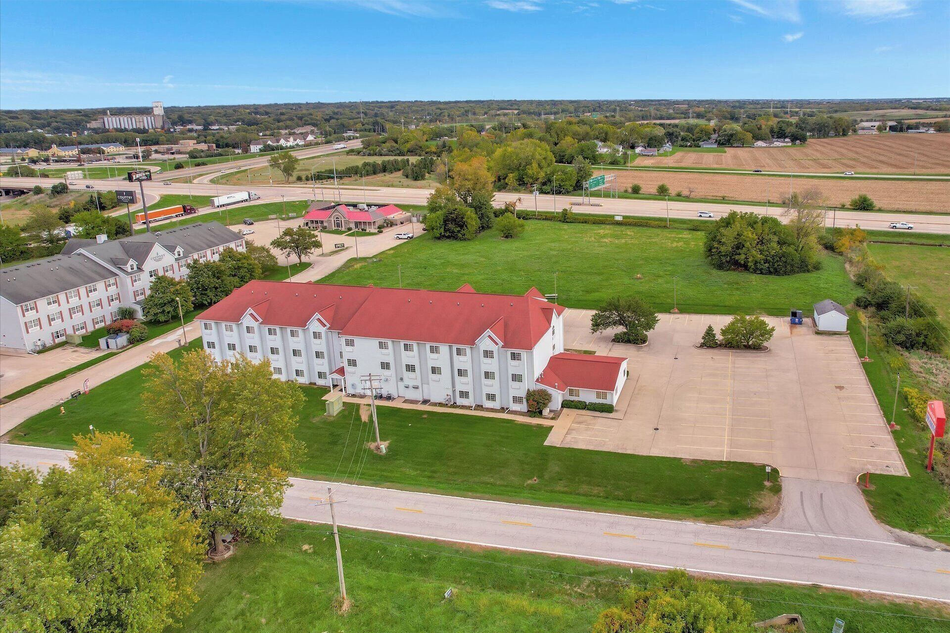 A large, white building with a red roof, surrounded by green lawns and a parking lot.