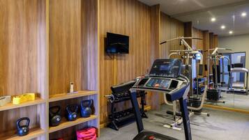 Une salle de sport équipée de tapis de course, d’appareils de musculation et de kettlebells.