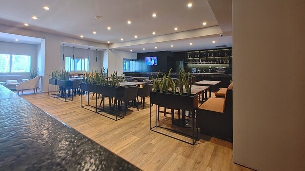 Un intérieur moderne comprenant un bar, des sièges et un écran de télévision.