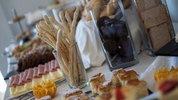 Uma mesa de buffet com diversos alimentos, incluindo palitos de pão, doces e sanduíches.
