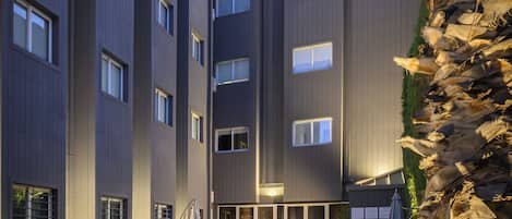 A modern building with multiple floors, outdoor seating, and a swimming pool.