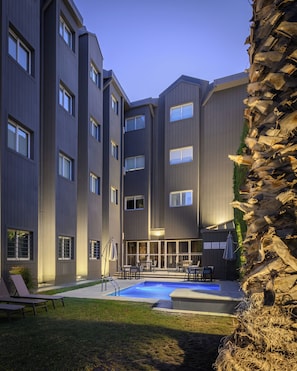 A modern building with multiple floors, outdoor seating, and a swimming pool. - Hathor Hotels Mendoza (Guaymallen)