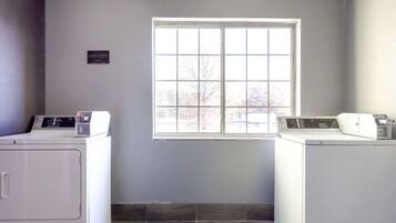 A laundry room with two washing machines, a window, and a sign indicating guest laundry hours.
