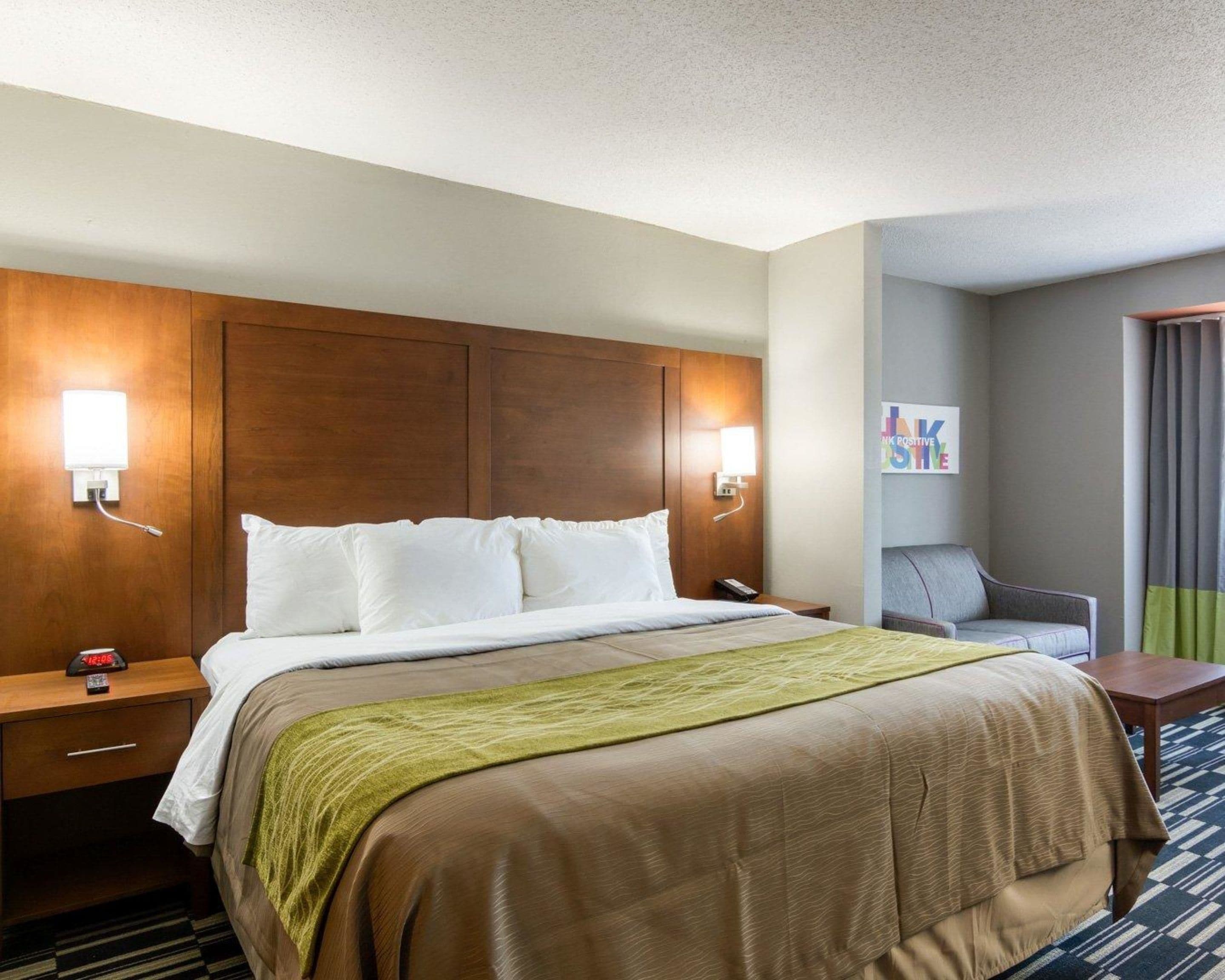 A hotel room with a large bed, two bedside tables, a nightstand, a chair, and a small table.