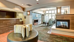 A hotel lobby with a reception desk, seating area, fireplace, and a view of the kitchen and dining area. - Residence Inn by Marriott Los Angeles LAX/El Segundo (El Segundo)