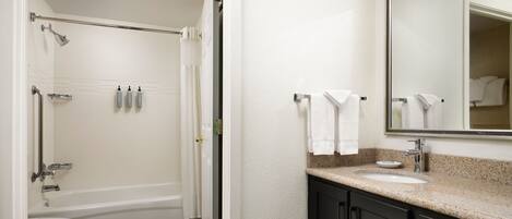 A bathroom with a bathtub, toilet, sink, and a large mirror.