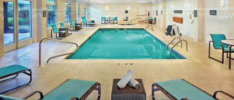 A hotel pool area with lounge chairs, a pool, and safety signs.