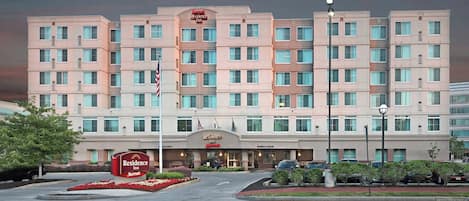 Un hotel de varios pisos con una entrada central, banderas estadounidenses y el logotipo de Marriott.
