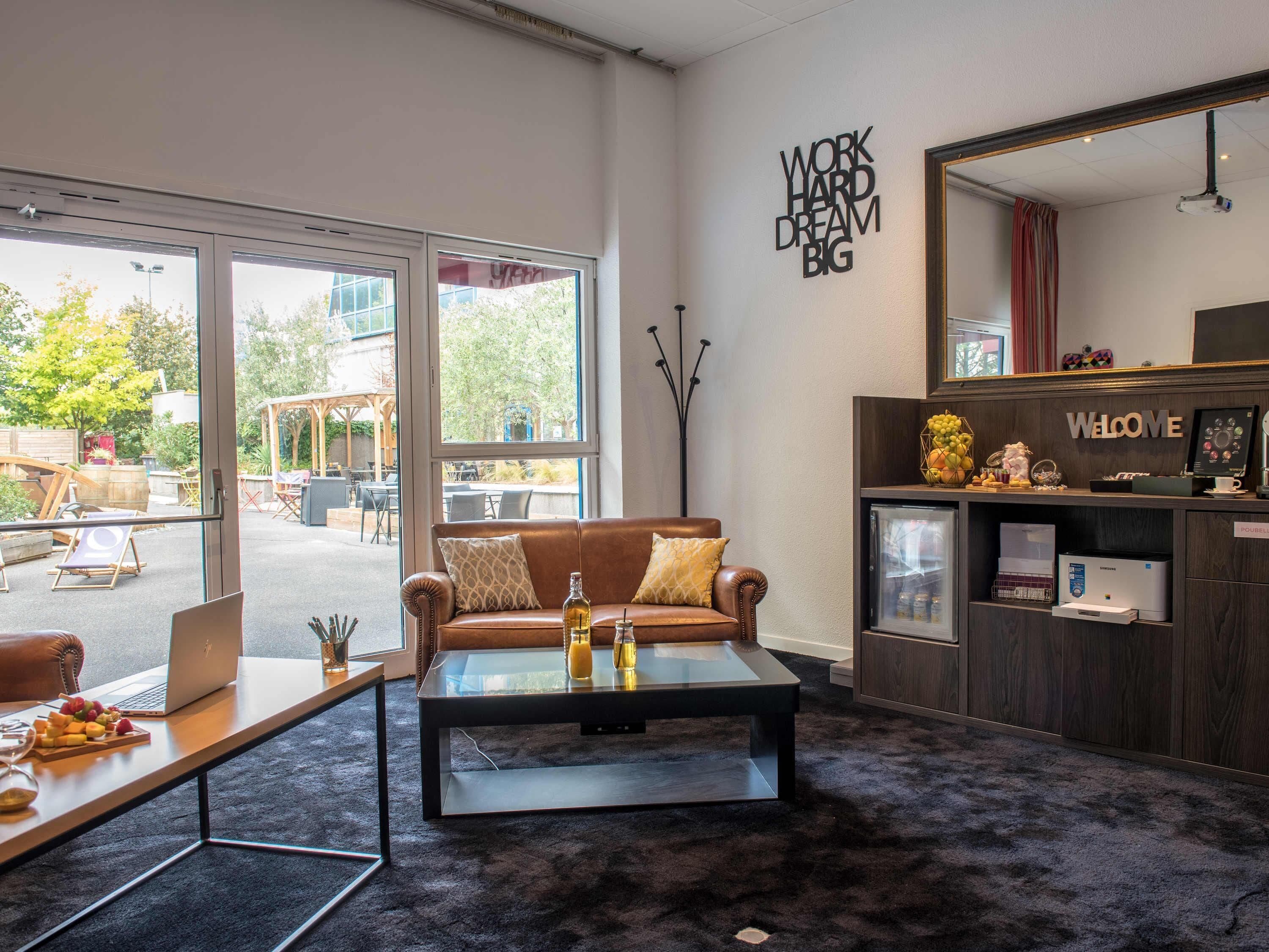 A modern interior with a leather sofa, a glass coffee table, a laptop, and a 'WORK HARD DREAM BIG' motivational wall.