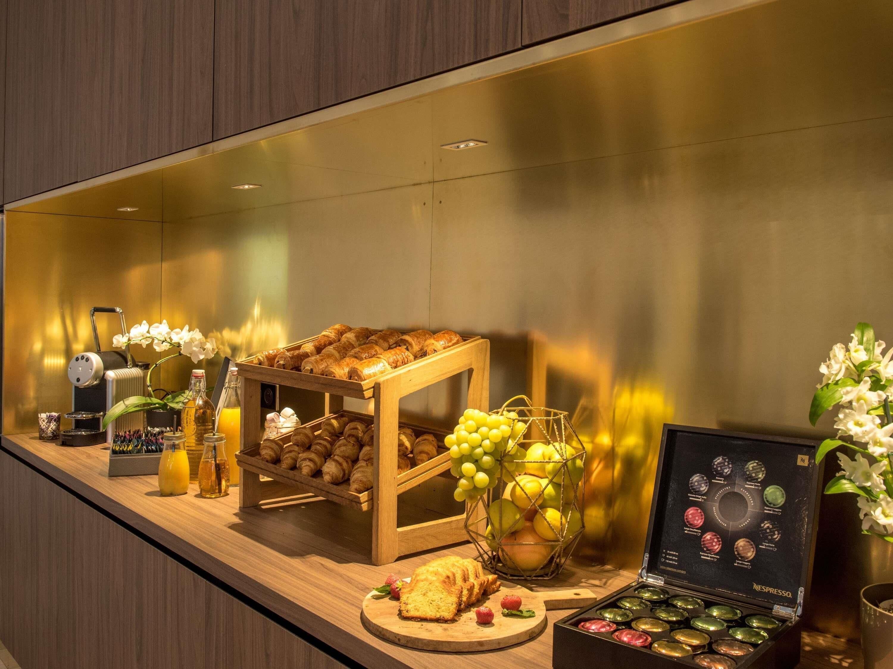 Un bufé de desayuno con pasteles, frutas y una máquina de café.