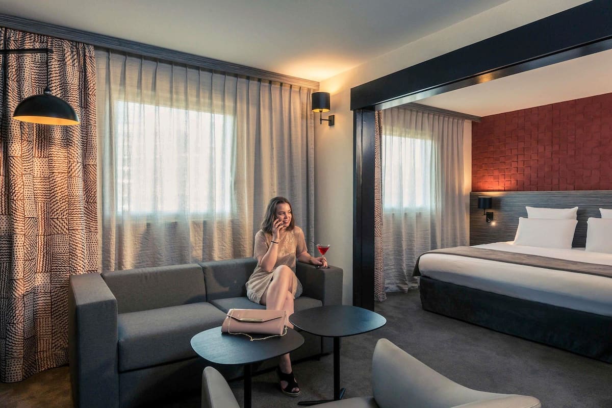 A modern hotel room with a bed, a sofa, a small table, and a chair.