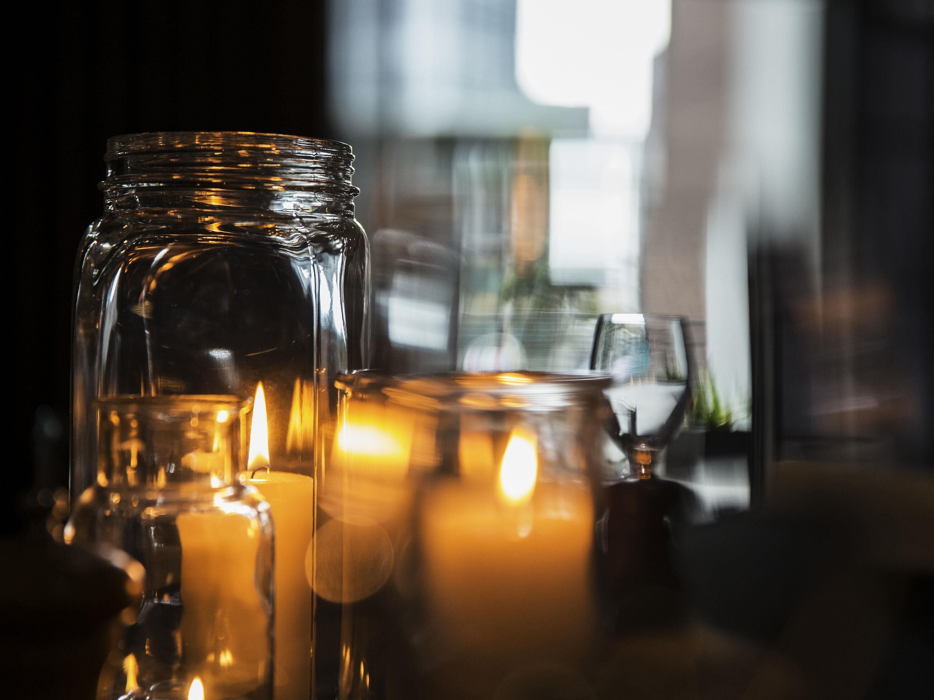 Un gros plan d’un bocal en verre contenant une bougie, posé sur une surface réfléchissante.