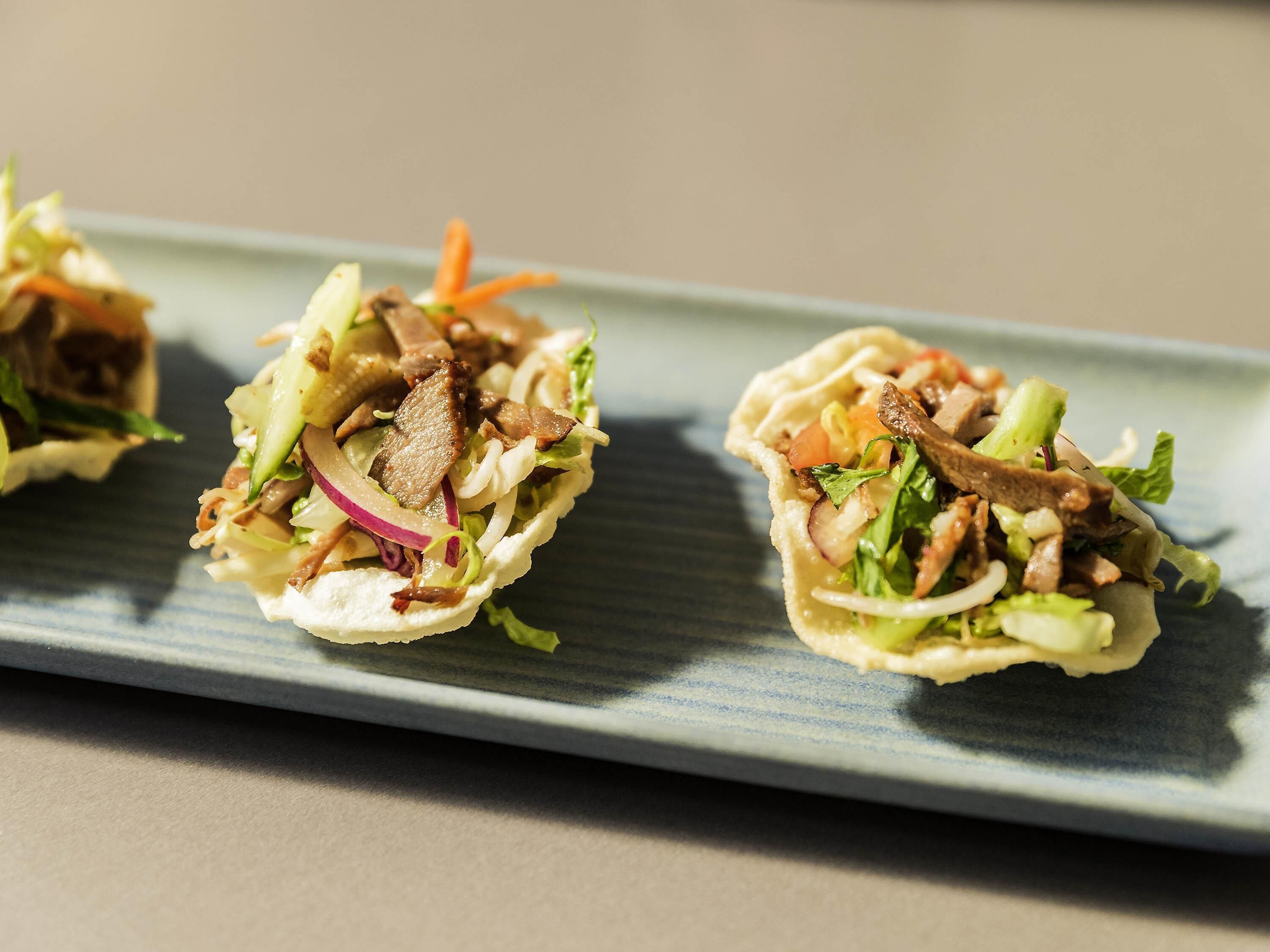 Three tacos on a rectangular plate.