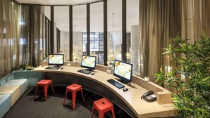 Un taulell de recepció modern amb tres monitors d'ordinador, un telèfon i una petita planta.