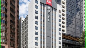 Un edifici d'hotel modern amb un senyal distintiu d''ibis', diverses plantes i façana de vidre.