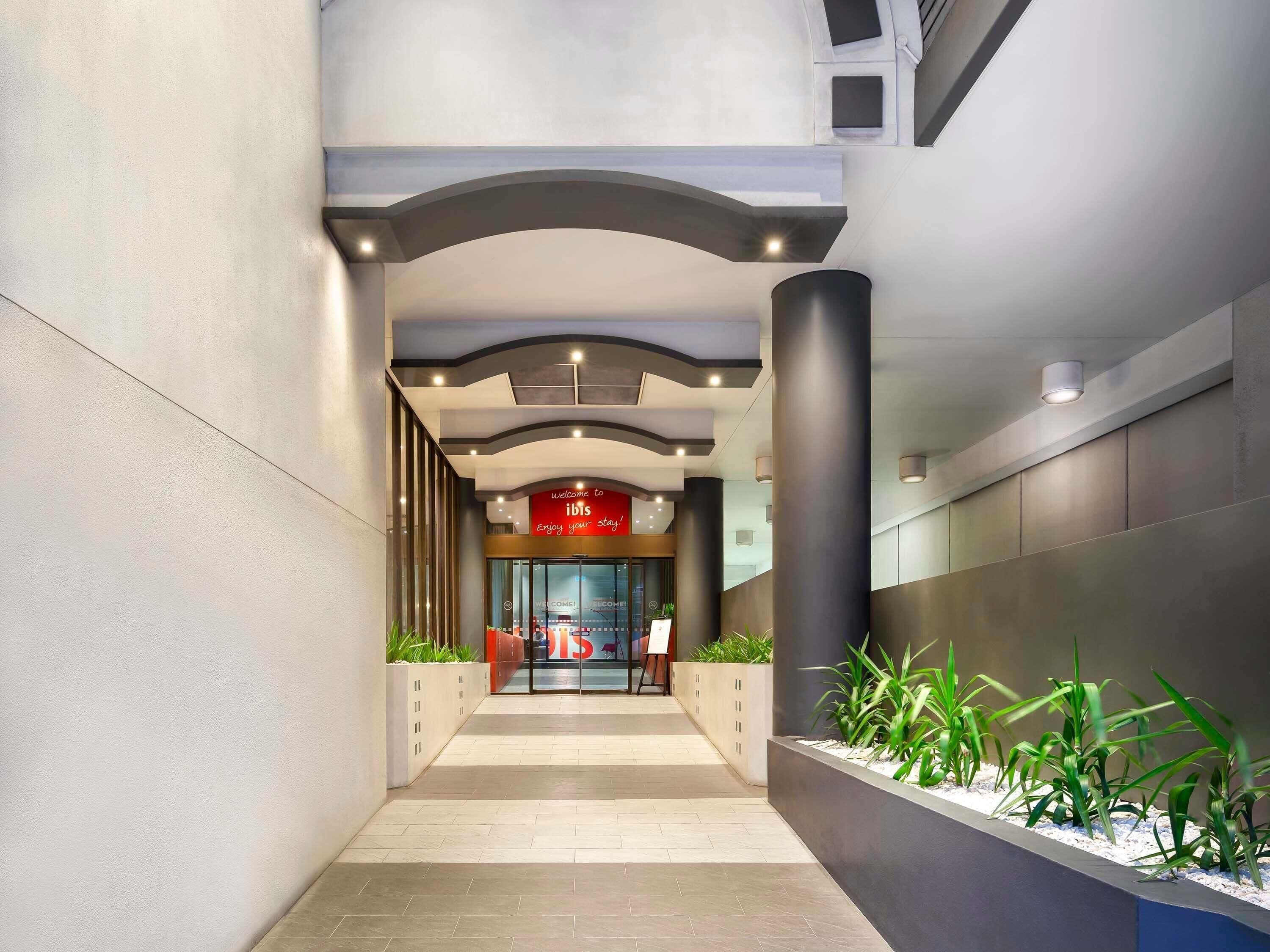 A modern hotel lobby with a curved ceiling, a reception desk, and a sign welcoming guests.