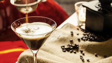 Um copo de martini com espuma, um coador de metal e grãos de café sobre um tecido.