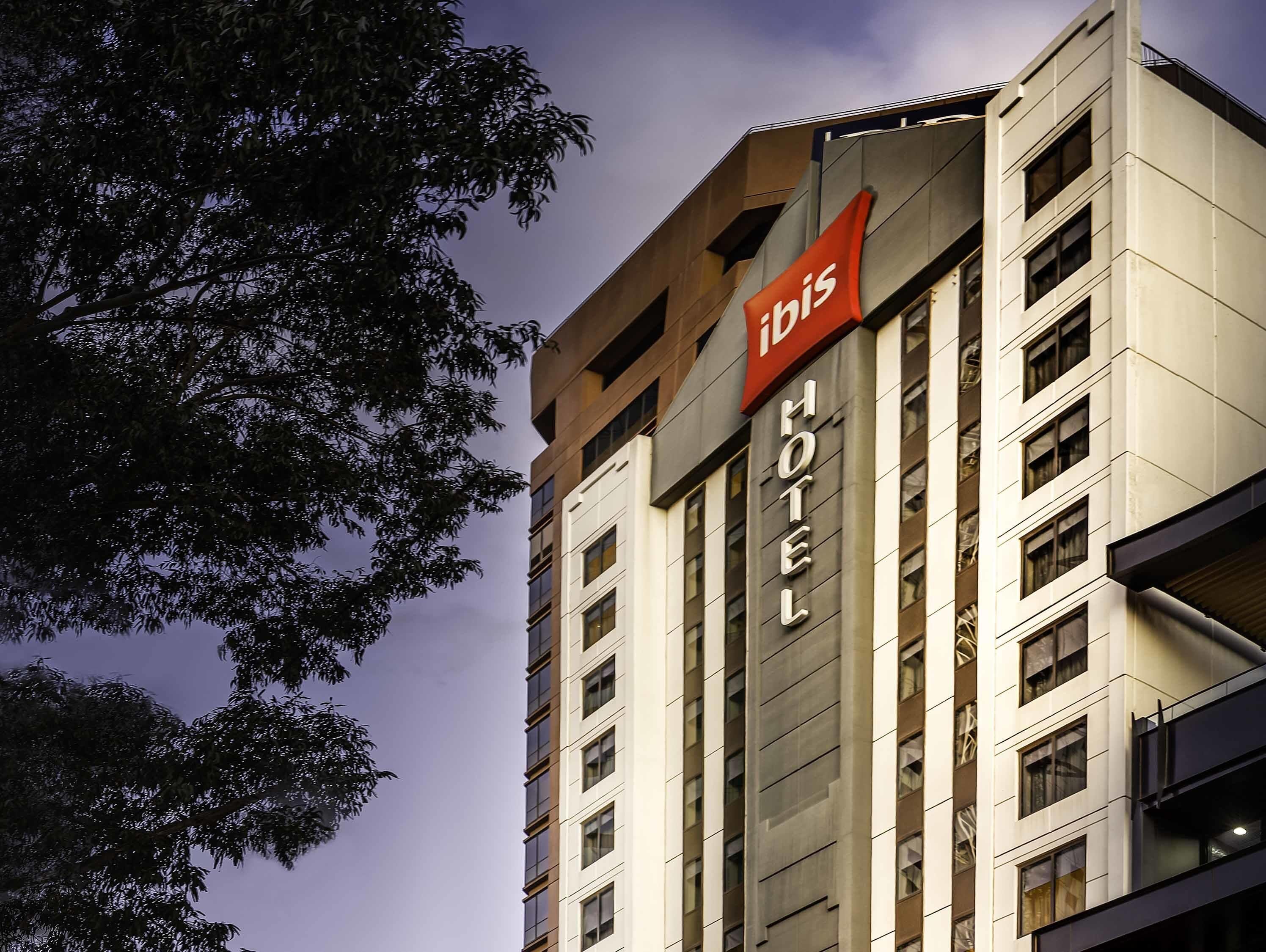 Un hôtel moderne, reconnaissable à son grand panneau rouge indiquant qu’il s’agit d’un hôtel Ibis.