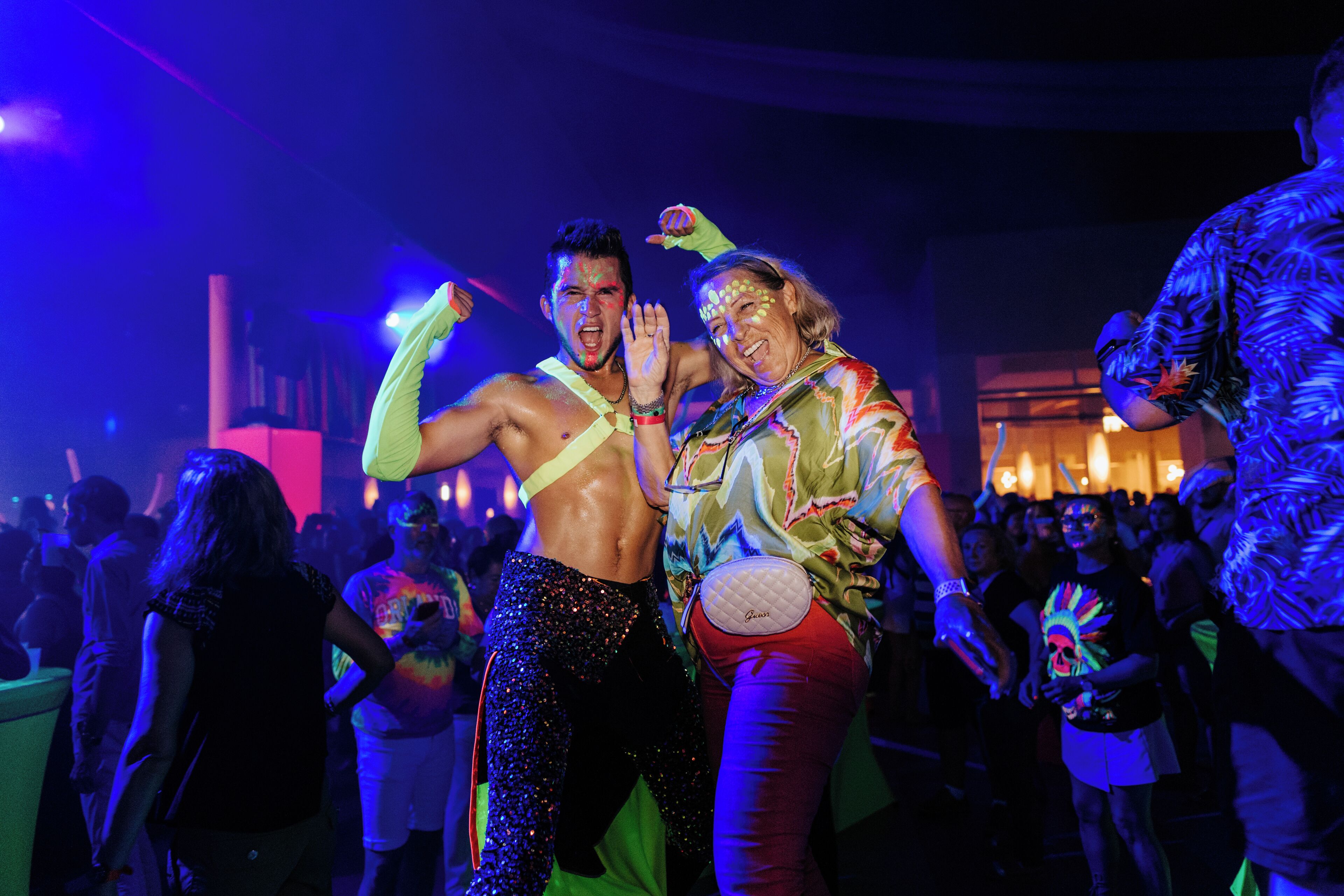 Evento interior concurrido donde personas bailan y conversan.