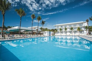 Relax by the pool surrounded by palm trees and lounge chairs.