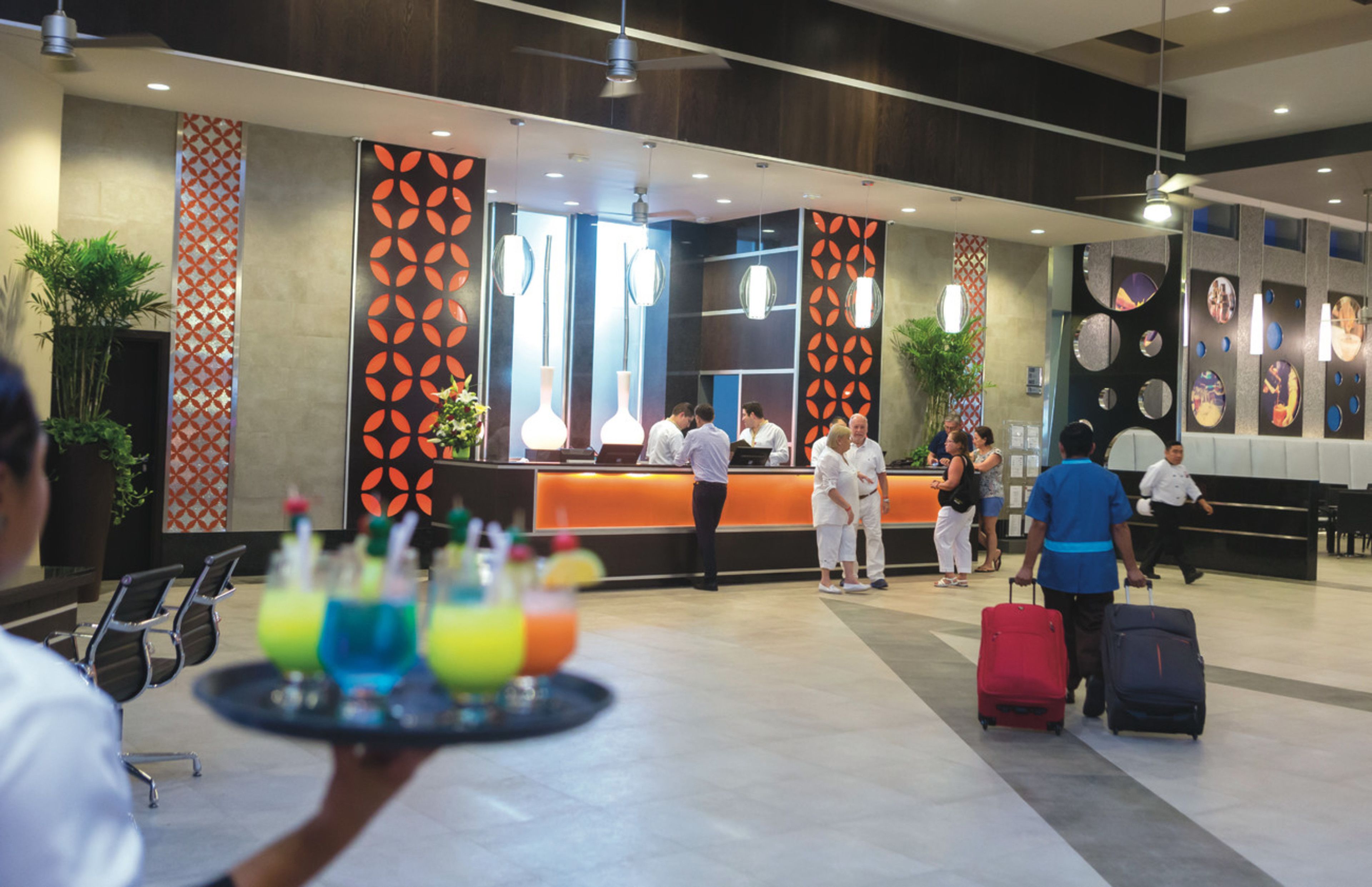 A hotel reception area with a modern design, featuring a reception desk, seating area, and decorative wall patterns.