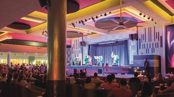A theater with a stage, audience seating, and a modern ceiling design.