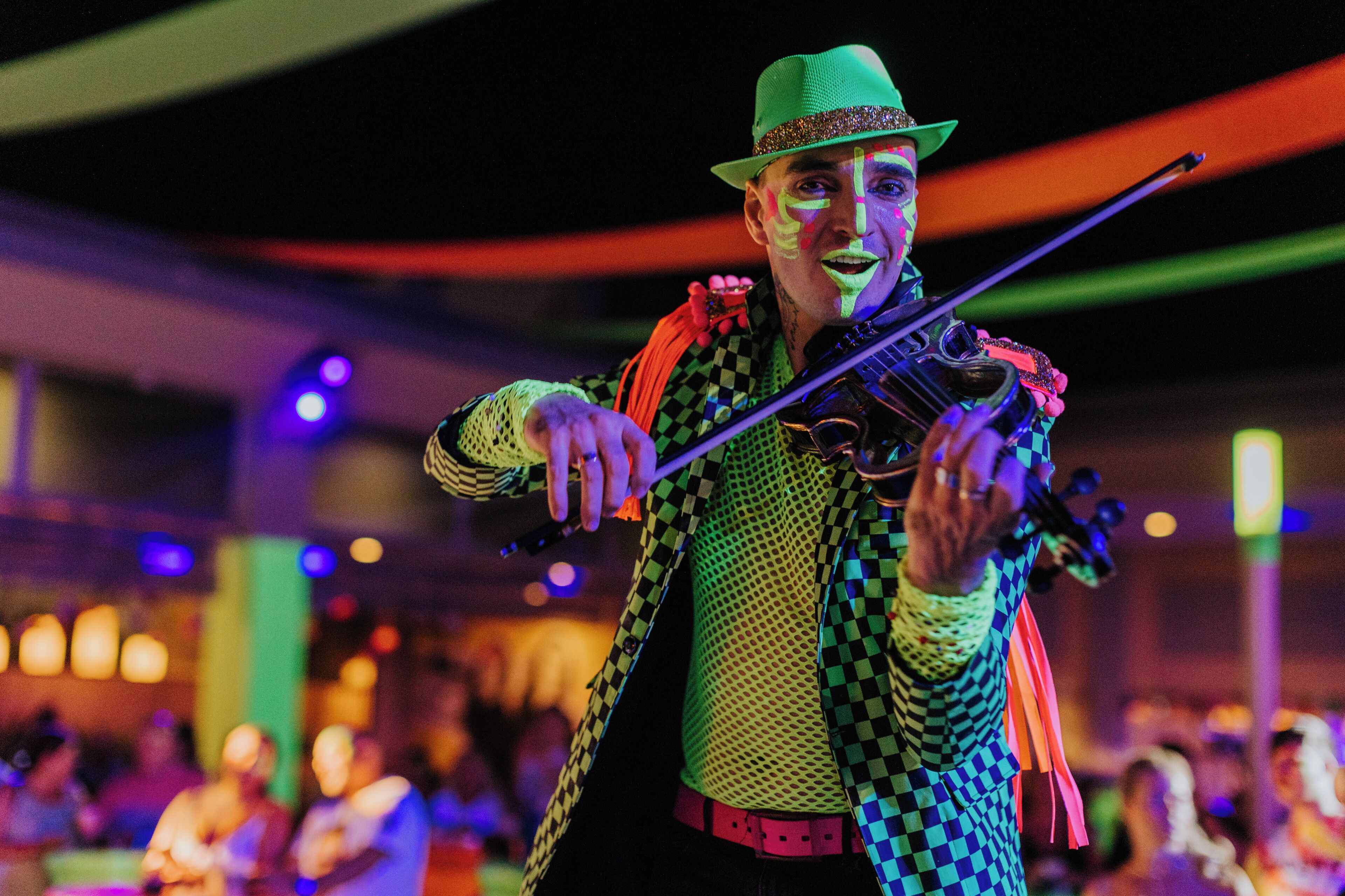 A person in a checkered jacket and hat playing a violin.