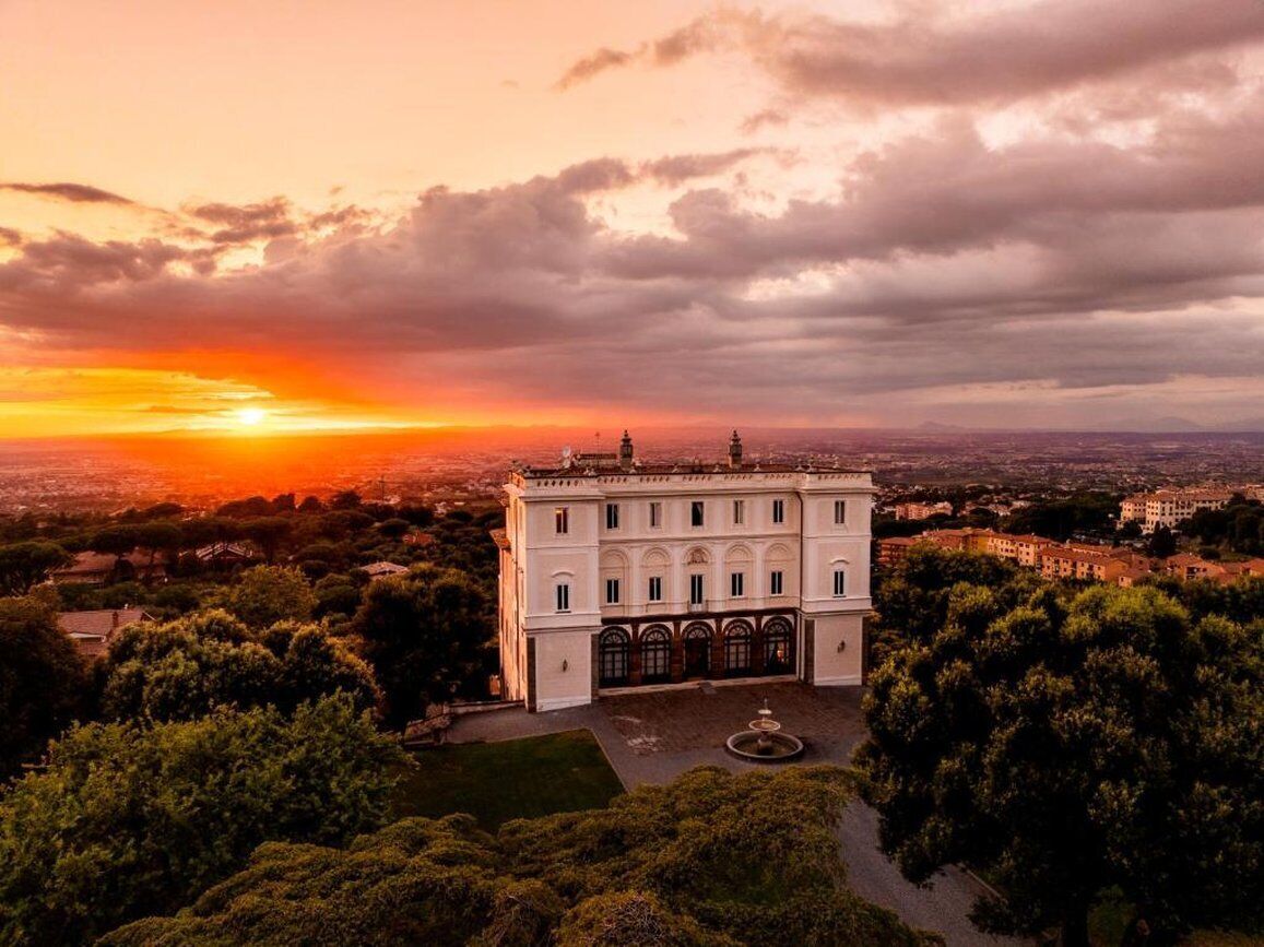 Un grande edificio storico con una facciata simmetrica, finestre ad arco e un cortile centrale con una fontana.