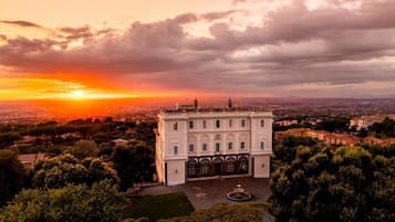 Un grande edificio storico con una facciata simmetrica, finestre ad arco e un cortile centrale con una fontana.