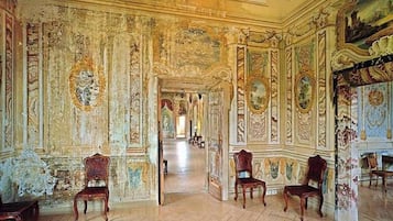 A grand hallway with ornate wall decorations and classical furniture.